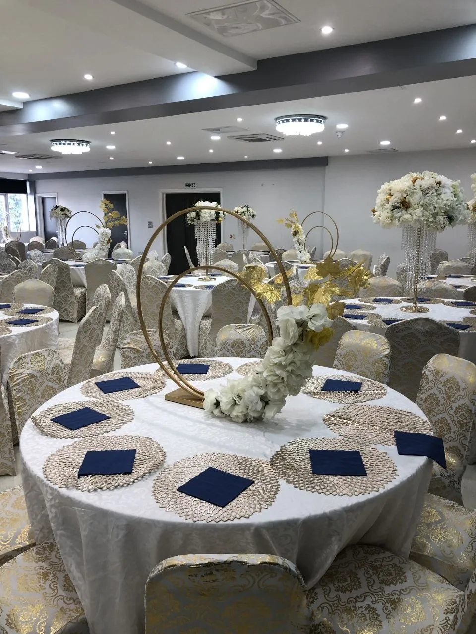 Navy and gold table styling with circular floral centrepieces in the P2 Centre hall, Erith