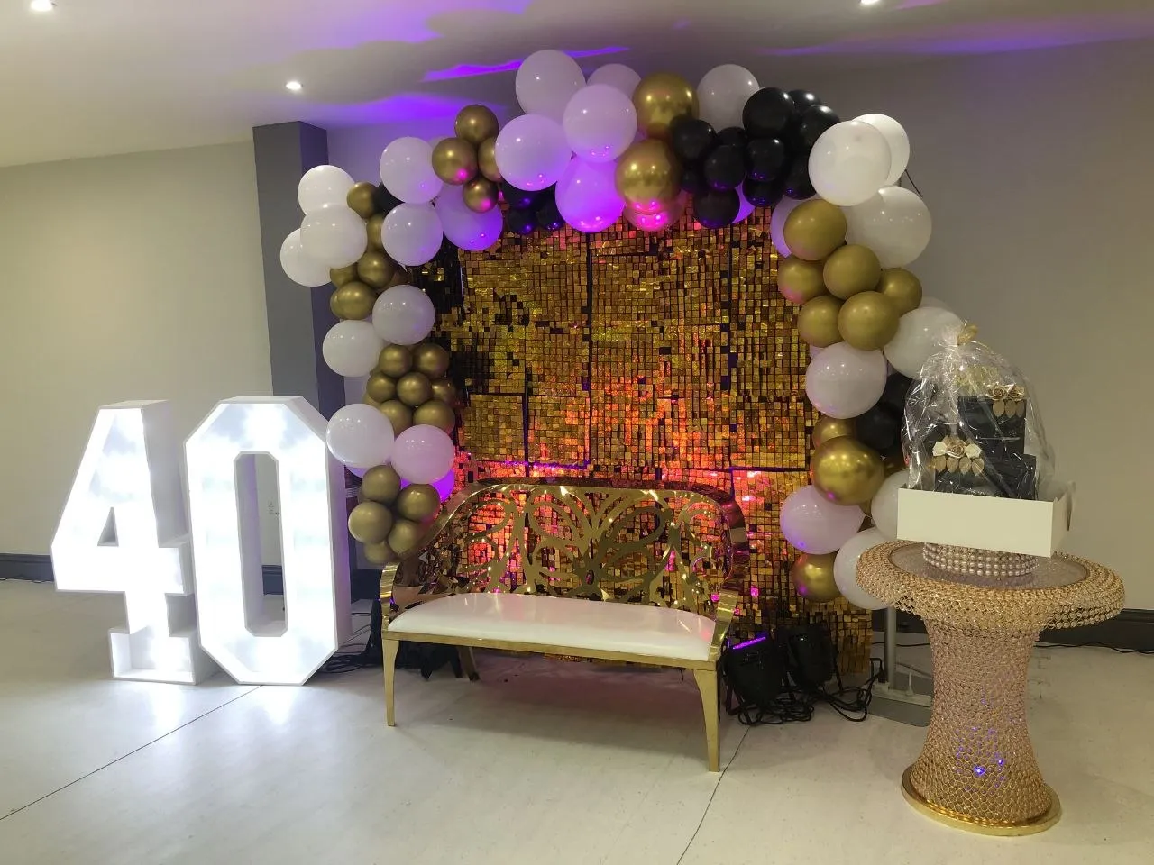 40th birthday photo area with gold sequin wall, balloons, light-up numbers and gold bench at P2 Centre, Erith