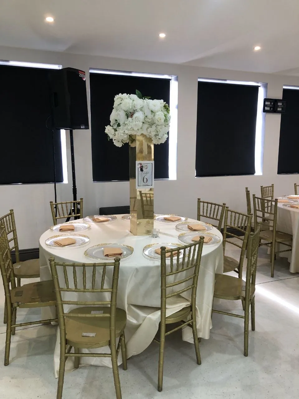 Round table with gold chiavari chairs and a white floral centrepiece in the P2 Centre function room, Erith