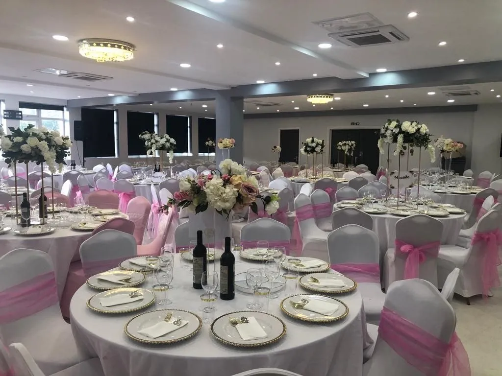 Wedding hall dressed in white and pink with floral centrepieces at P2 Centre, Erith
