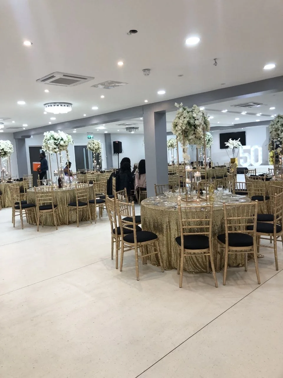 Gold sequin tables and chiavari chairs set for a 50th birthday party in the P2 Centre hall, Erith
