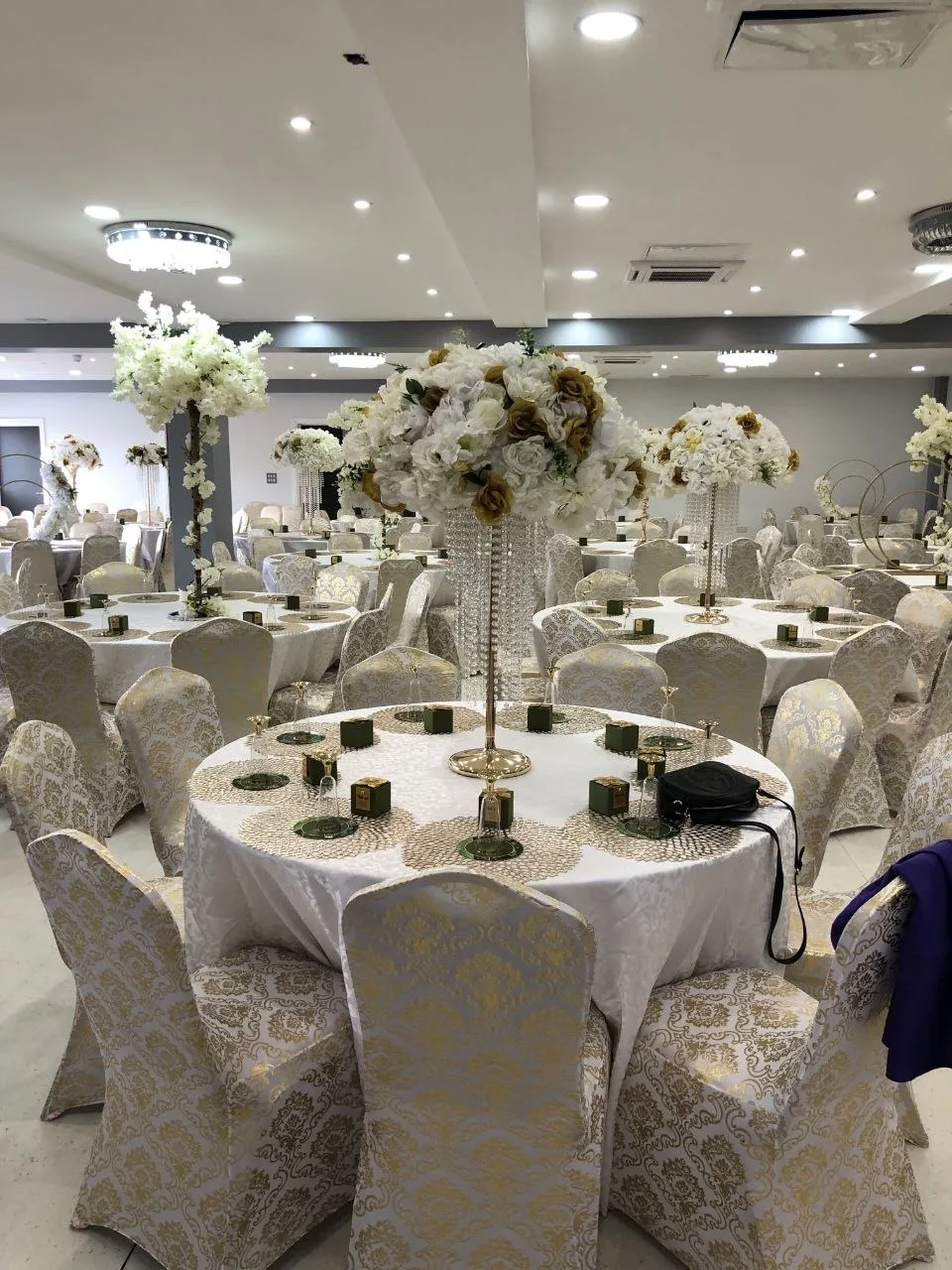 Banquet tables with white and gold floral centrepieces in the P2 Centre event hall, Erith
