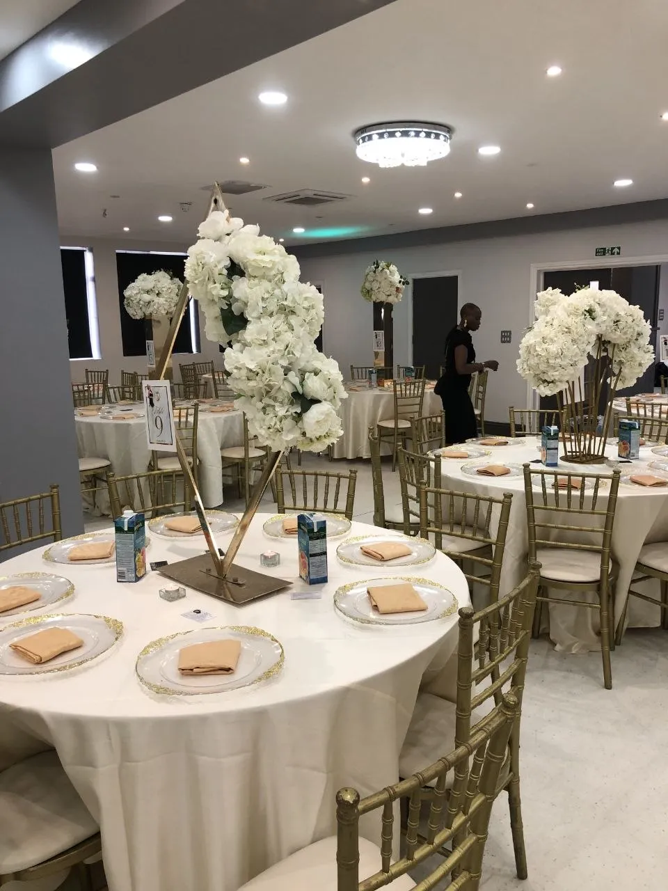 White floral table centrepieces and gold-rimmed plates across the P2 Centre hall, Erith