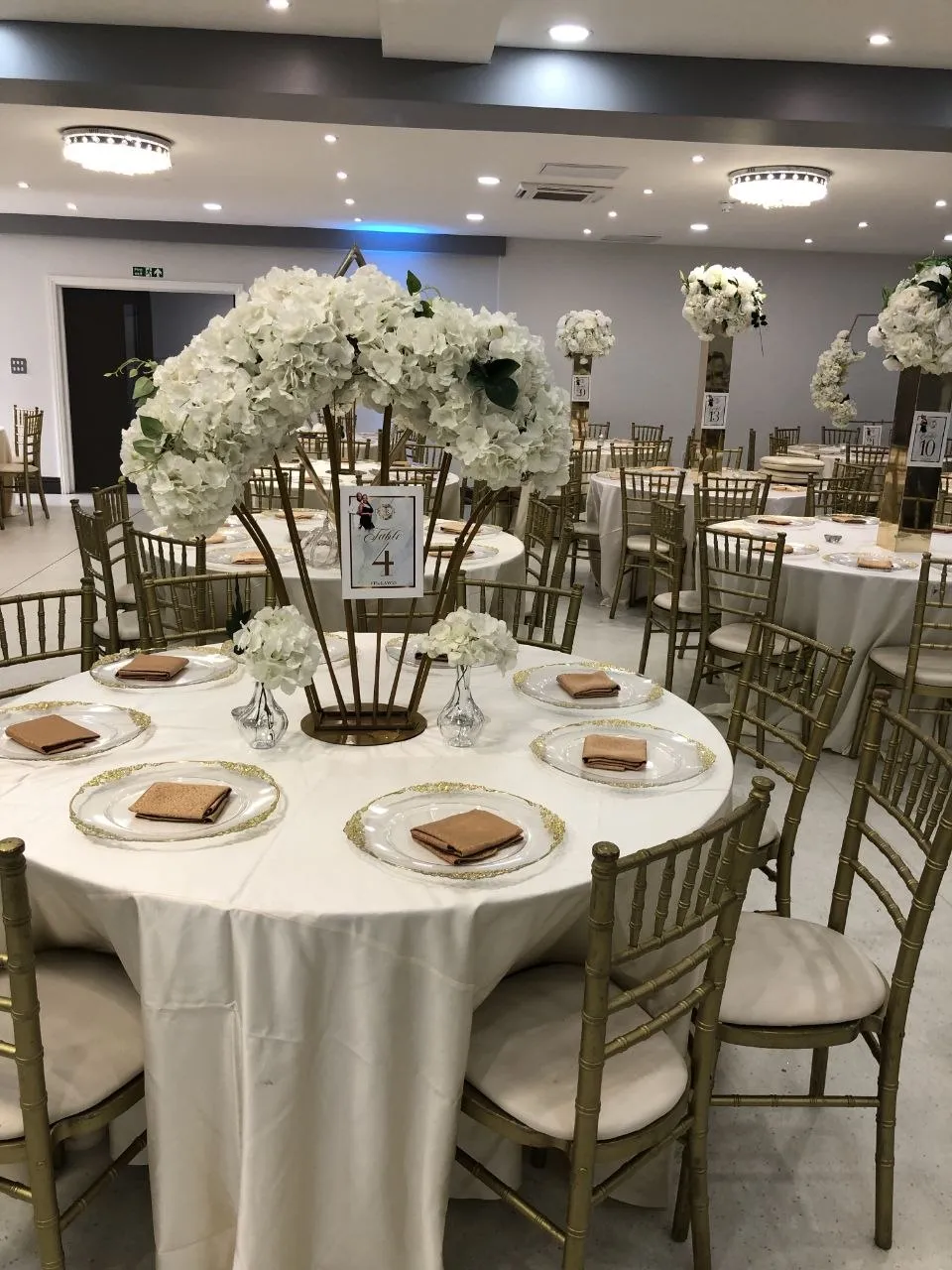 Round tables with gold chiavari chairs and white hydrangea centrepieces at P2 Centre, Erith