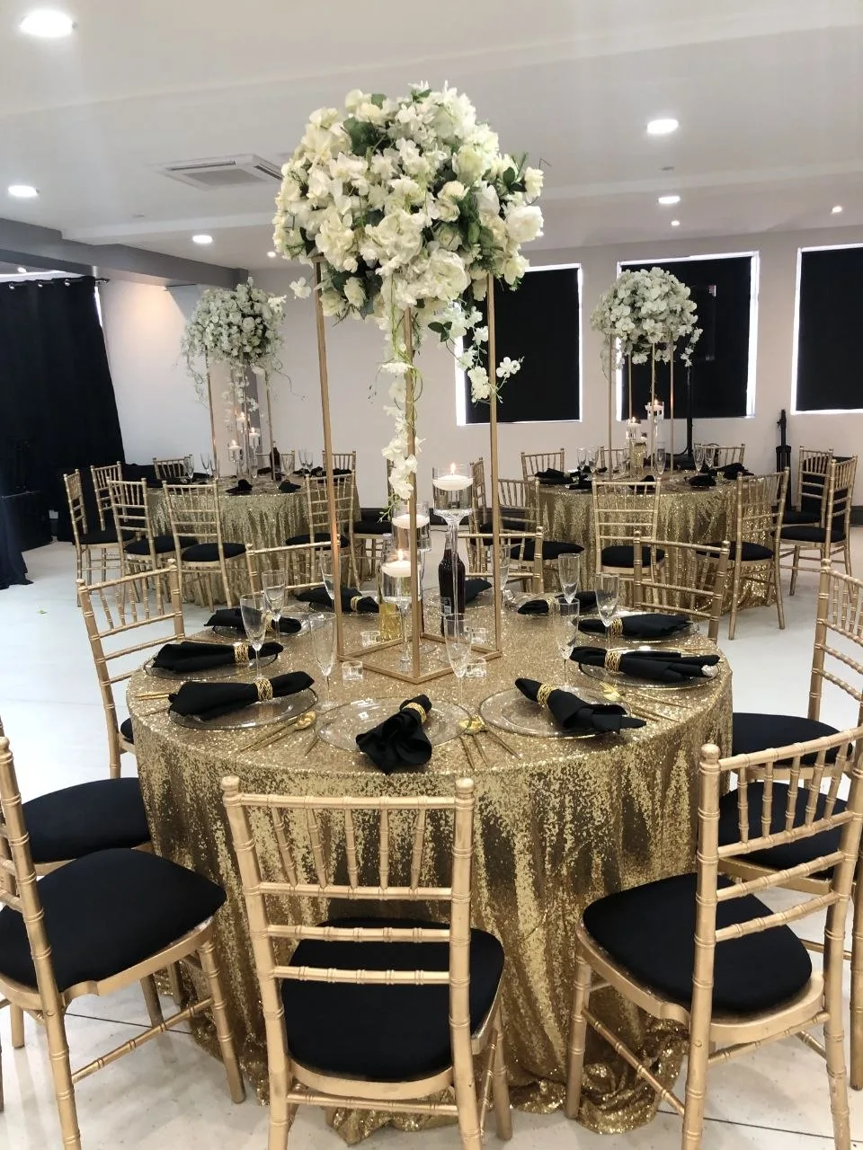 Black and gold birthday table setting with tall white floral centrepiece at P2 Centre, Erith