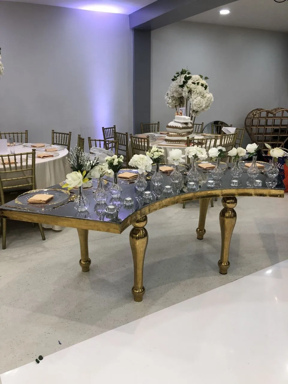 Curved gold top table with mirrored top, bud vases and tea lights at P2 Centre, Erith