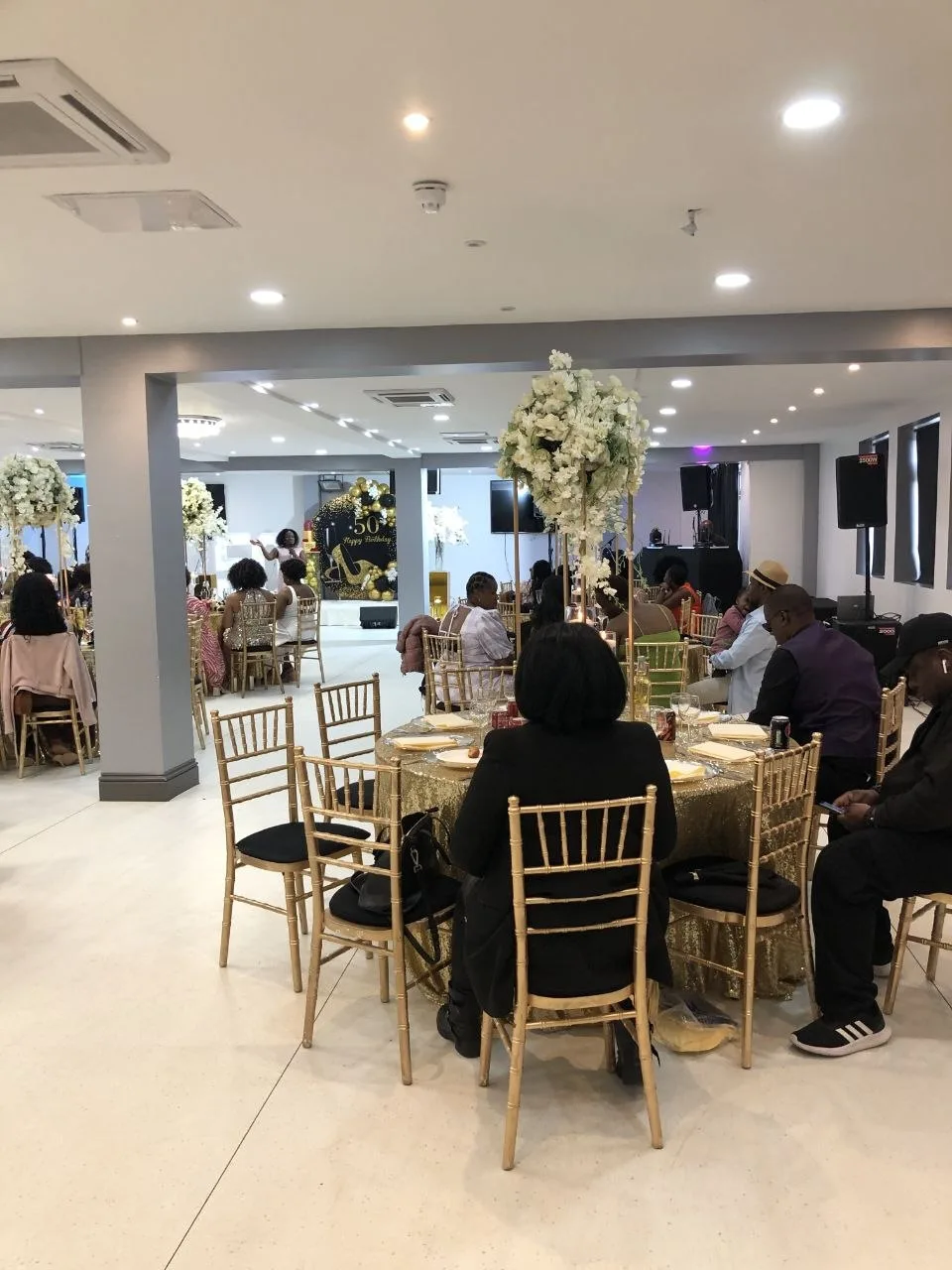 Guests at a 50th birthday celebration with gold chiavari chairs at P2 Centre event venue, Erith