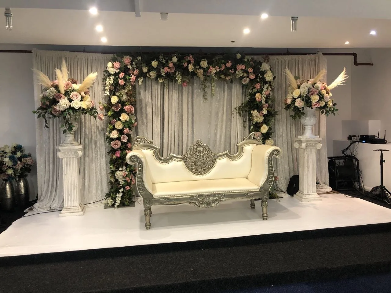 Wedding stage with floral arch and ivory throne sofa at P2 Centre wedding venue, Erith